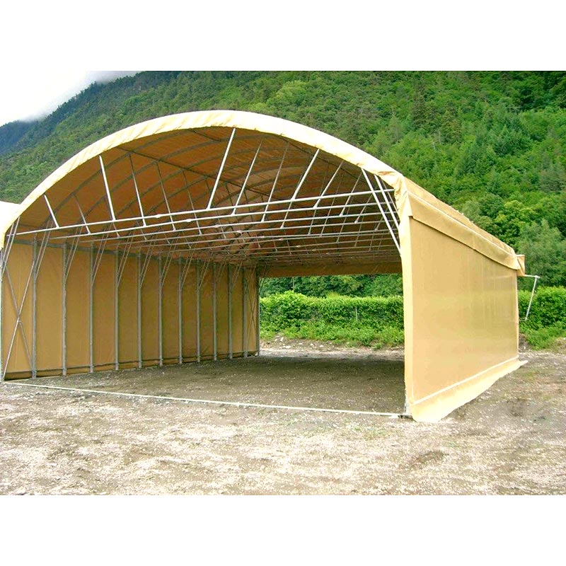 Tunnel de stockage en PVC, vu de profil à mi-distance, avec une forêt en arrière-plan.
