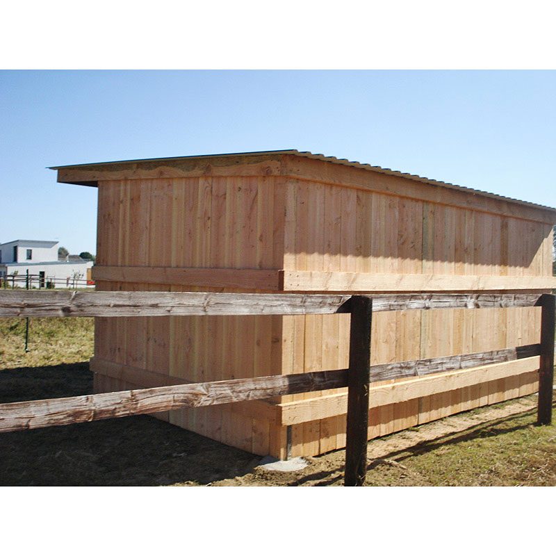Abri à bardage, vue de dos de près, collé à une clôture en bois.