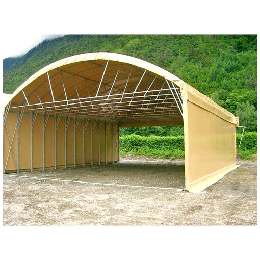 Tunnel de stockage en PVC, vu de profil à mi-distance, avec une forêt en arrière-plan.