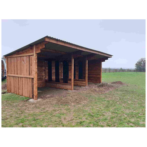 Double abri pour chevaux avec distributeur de foin central, vue de profil à mi-distance.